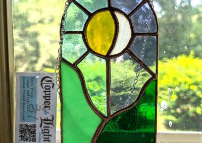 Image of a stained glass sun and moon over a green landscape | Copper & Light Studio